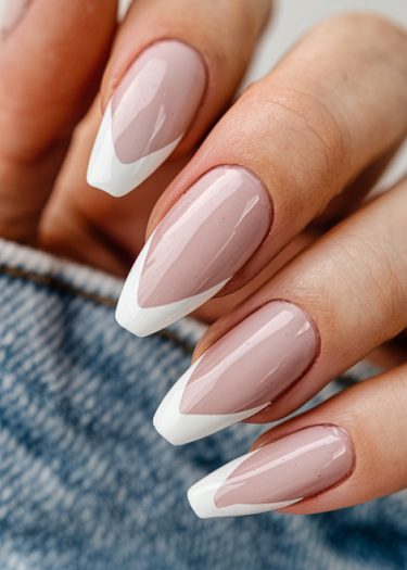 Elegant French manicure with pointed almond nails in soft pink and bold white tips.