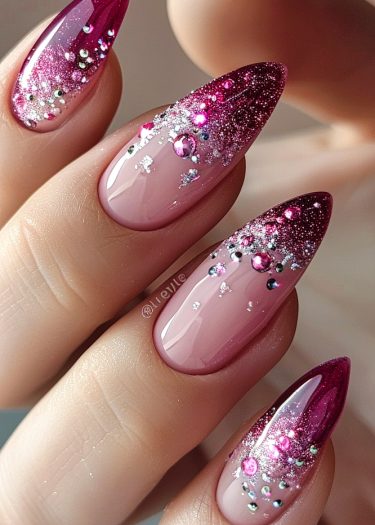 Elegant stiletto nails featuring fuchsia glitter and rhinestones for a stunning ombre look.