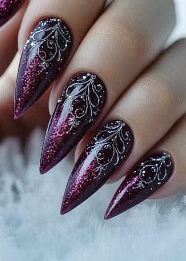 Elegant stiletto nails with burgundy polish and intricate silver designs showcasing nail art sophistication.