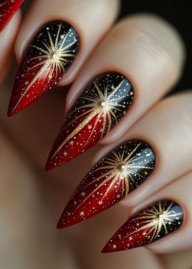 Stiletto nails featuring black and red gradient with luxurious gold starburst designs.