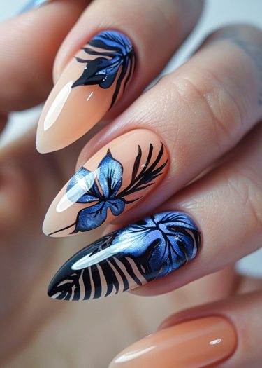 Elegant gradient nail art featuring floral designs in metallic blue and black on nude nails.