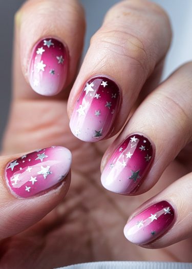 Elegant ombre nail art featuring burgundy to pink gradient with silver star designs.