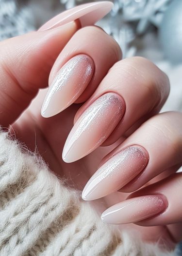 Elegant ombre nails with silver glitter on a soft, cozy background.