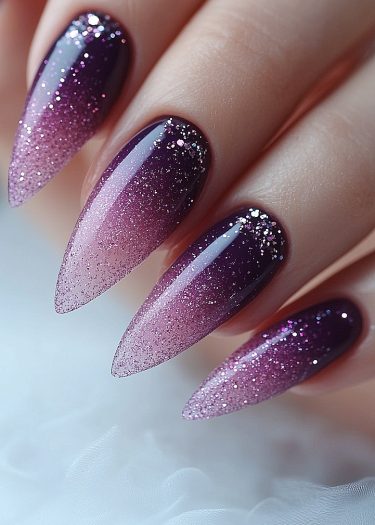 Elegant almond-shaped gradient nails with purple and pink hues, adorned with sparkling glitter.