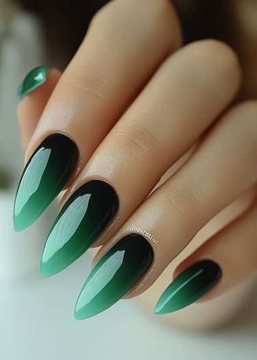 Elegant almond-shaped nails feature a striking black-to-green gradient design in this manicure.