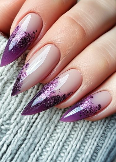 Stunning stiletto nails with gradient purple and nude design, embellished with glitter.