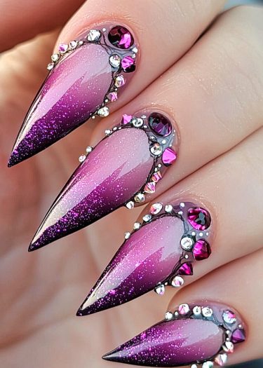 Elegant stiletto nails feature a sparkling ombre design with gemstones for a glamorous look.