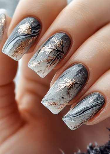 Elegant nail art featuring gradient gray and black with gold leaf designs and glitter accents.