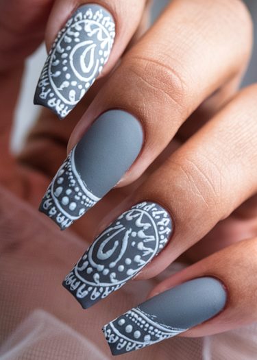 Elegant gray henna nail art features intricate patterns on a matte finish, showcasing artistic design.