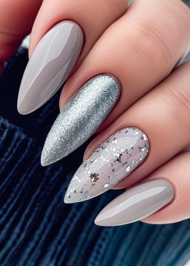 Stylish stiletto nails featuring glossy grey and sparkling silver glitter designs for elegant nail art.