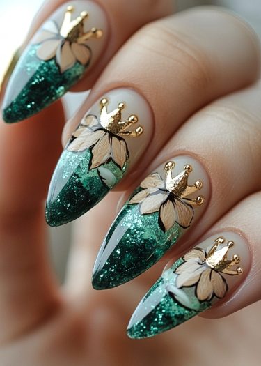 Elegant green glitter nails with floral designs and gold crowns for a sophisticated look.