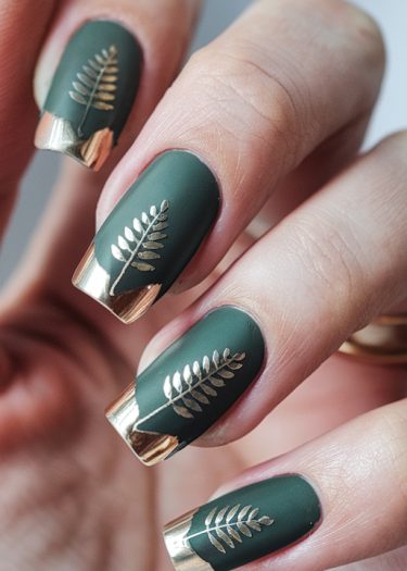 Elegant forest green matte nails with gold tips and botanical designs for a modern look.