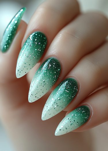 Elegant green and white gradient stiletto nails with glitter for a chic manicure look.