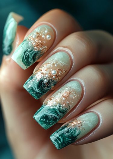 Elegant green marble nail art with gold glitter and pearls for a chic, luxurious look.