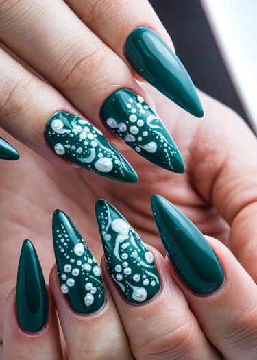 Elegant stiletto green nails with intricate white art and three-dimensional accents.