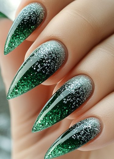 Stiletto nails featuring a stunning green to silver gradient with glitter accents and glossy finish.