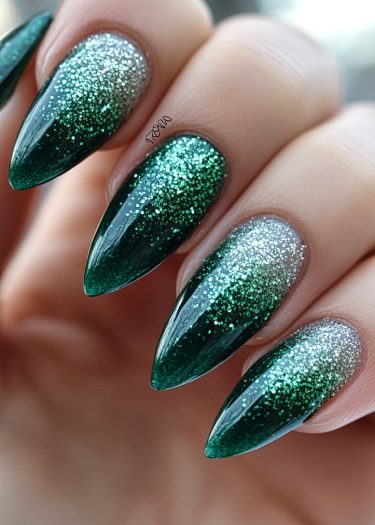 Elegant stiletto nails feature a green and silver gradient with sparkling glitter accents.