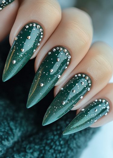 Elegant green stiletto nails with silver studs, creating a luxurious and festive manicure.