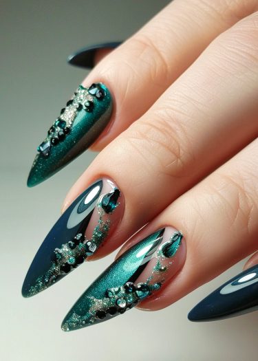 Elegant teal stiletto nails with intricate rhinestone embellishments for a sophisticated manicure look.