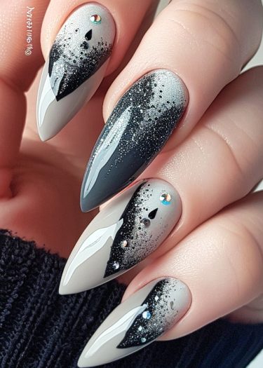 Elegant stiletto nails with gray ombre and black glitter accents, featuring rhinestone embellishments.