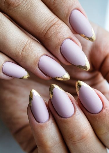 Sophisticated matte pink manicure with elegant gold foil tips on long almond-shaped nails.