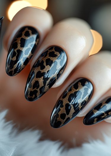 Elegant stiletto nails featuring glossy black and gold leopard print nail art design.