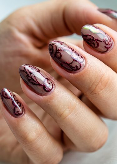 Elegant mauve almond-shaped nails featuring intricate burgundy designs and glossy finish.