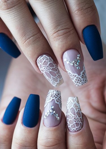 Elegant coffin-shaped nails with matte blue and lace designs, featuring chic rhinestone accents.