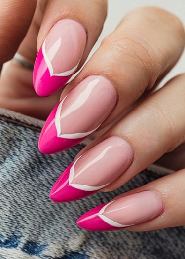 Elegant stiletto manicure with vibrant hot pink tips and geometric design on denim background.