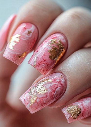 Exquisite marble nail art with gold leaf accents on elegant, manicured nails.