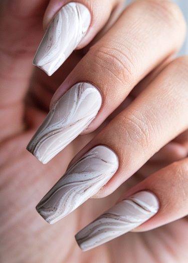 Elegant marble nail art with a glossy finish in soft neutral colors.