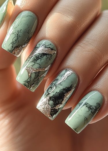 Elegant marble nails in pastel green with glossy black veining and silver shimmer accents.