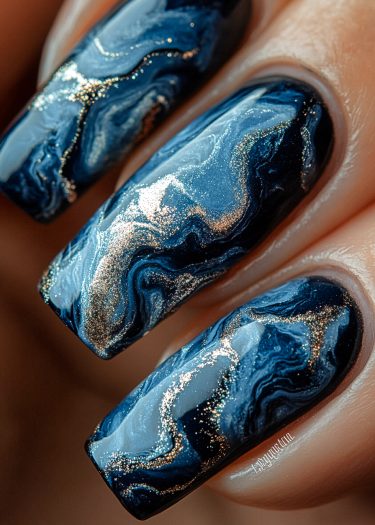 Elegant marbled nails with deep blue, black, and shimmering gold accents for a luxurious manicure.