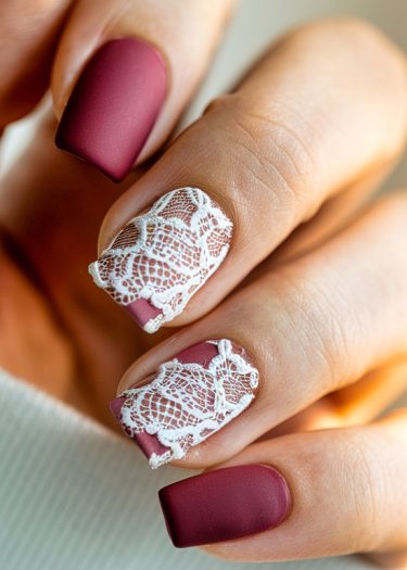 Elegant burgundy matte nails with intricate lace design showcase sophisticated nail art craftsmanship.