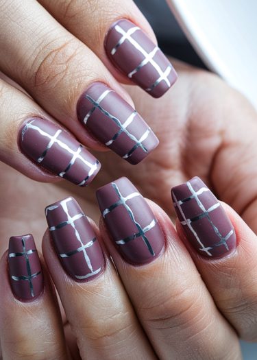 Stylish maroon nail art with silver geometric design on elegantly shaped nails.