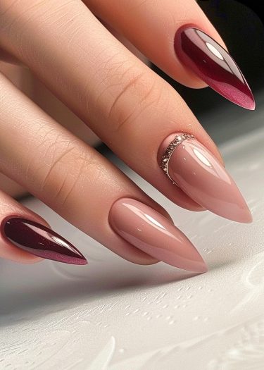 Elegant maroon and nude nail art with stiletto shape and sparkling embellishments.