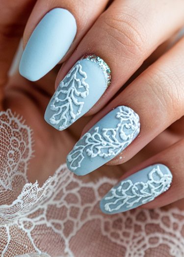 Elegant matte blue nails with intricate white lace designs and sparkling embellishments for a sophisticated look.