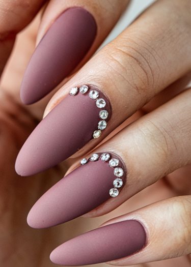 Elegant mauve matte nails with rhinestones for a sophisticated manicure look.