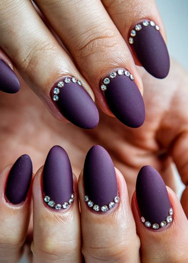 Elegant matte purple nails with rhinestone accents showcasing sophistication and style.