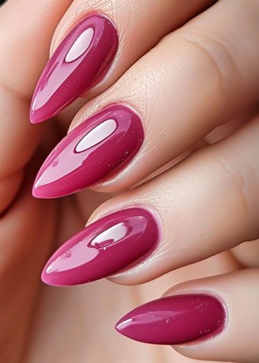 Elegant almond-shaped nails in glossy magenta, showcasing a professional manicure and vibrant color.