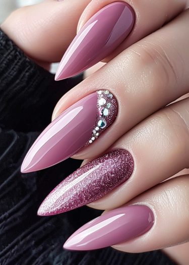 Elegant mauve stiletto nails with glitter and rhinestones for a sophisticated manicure.