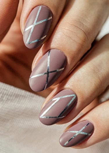 Elegant mauve nail art with metallic geometric designs on almond-shaped nails.