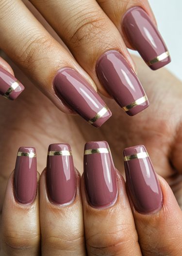 Elegant mauve nails with gold stripes, showcasing a chic and modern manicure design.