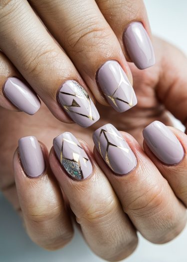 Elegant mauve nails with geometric gold designs and glitter accents for a chic manicure.