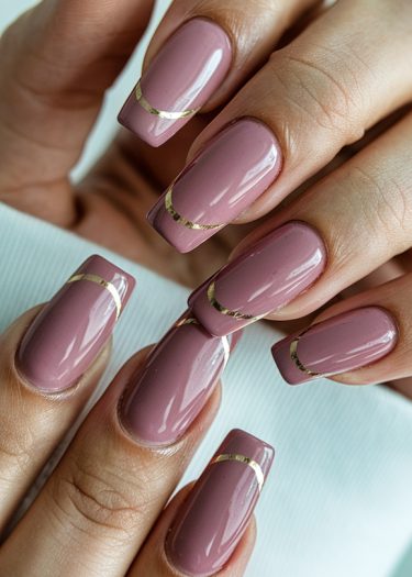 Stylish mauve nails with gold stripes, showcasing elegant manicure art and modern design.