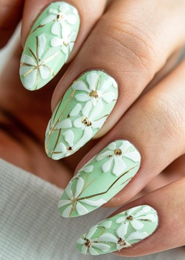 Elegant mint green floral nails with white flowers and gold accents for a sophisticated manicure.