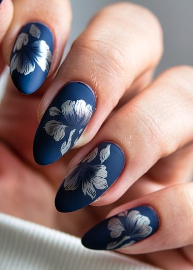 Elegant navy nail art featuring hand-painted white hibiscus flowers in a matte finish.