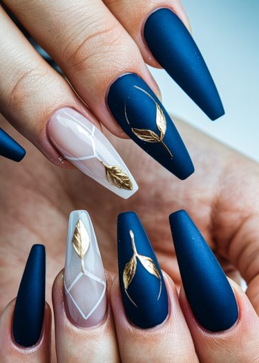 Elegant navy stiletto nails featuring matte finish, geometric designs, and gold leaf accents.