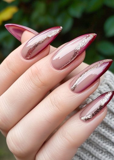 Elegant nude and burgundy nail art with gold accents for a sophisticated manicure look.