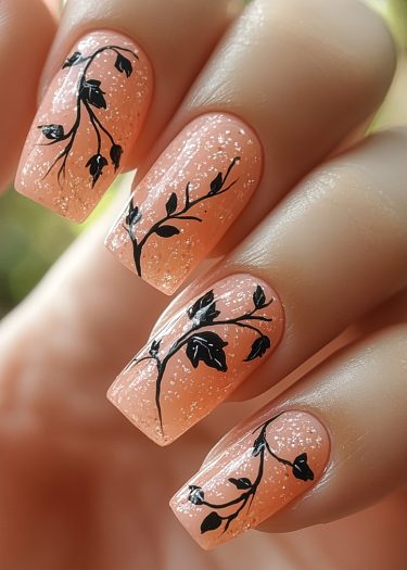 Elegant nude glitter nails with intricate black vine designs for a stylish, feminine look.